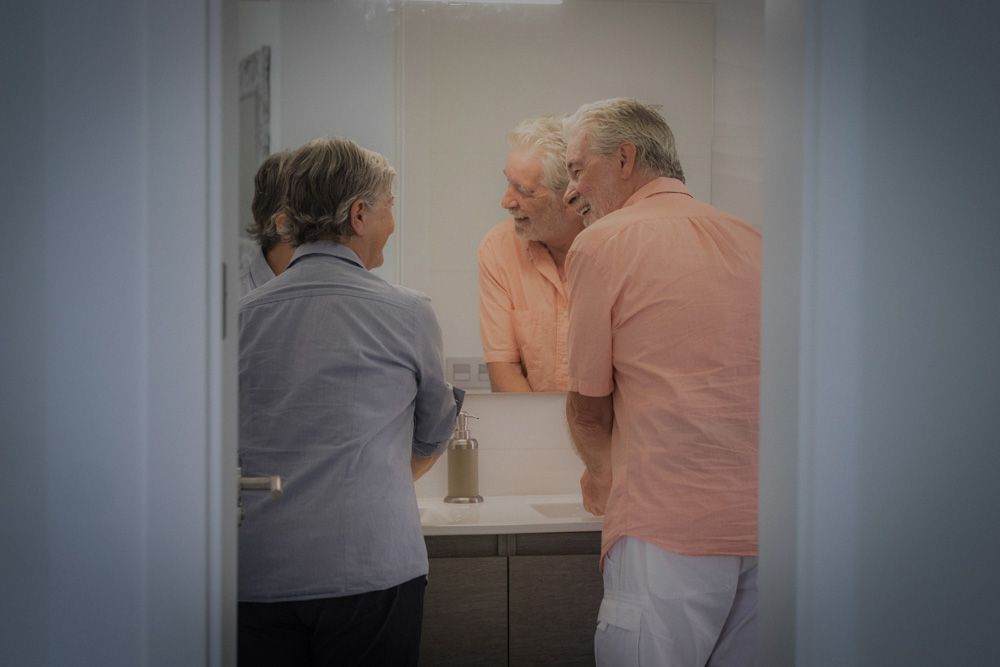 Couple chatting as they use the basin in the bathroom