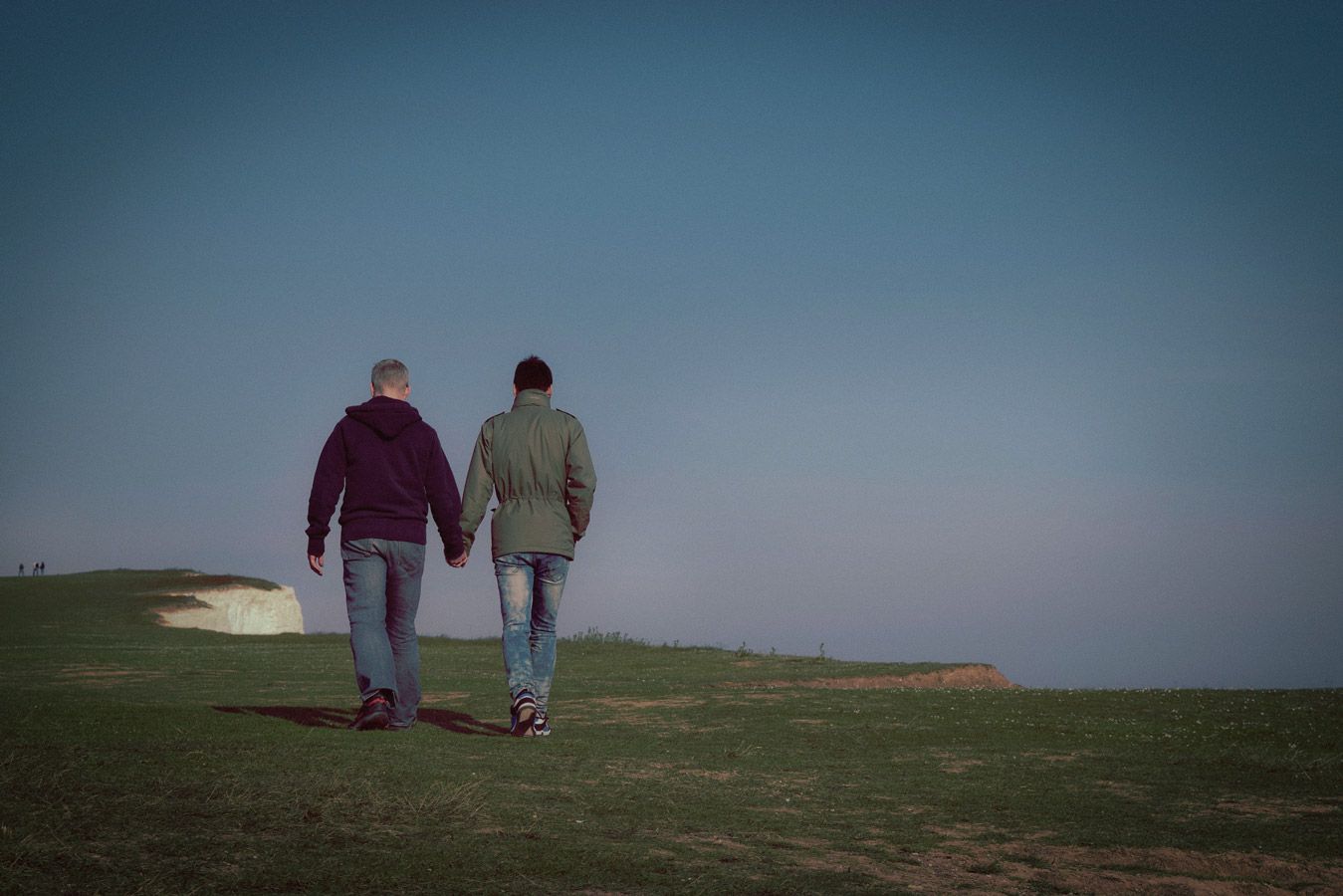Two men walking holding hands and walking on cliff top