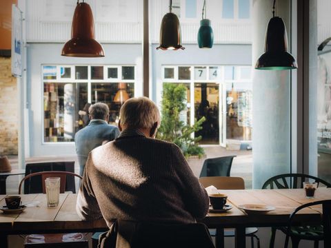 Back view of older man sitting at a cafe