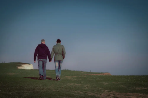 Two men walking holding hands and walking on cliff top