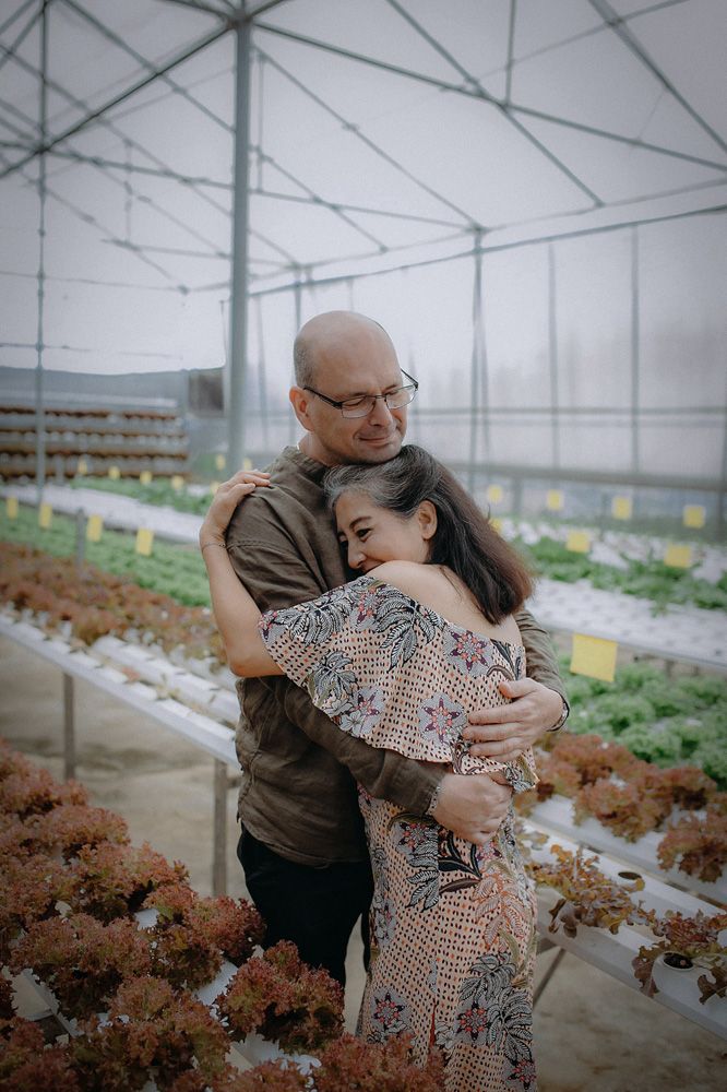 Older man and woman embracing in greenhouse
